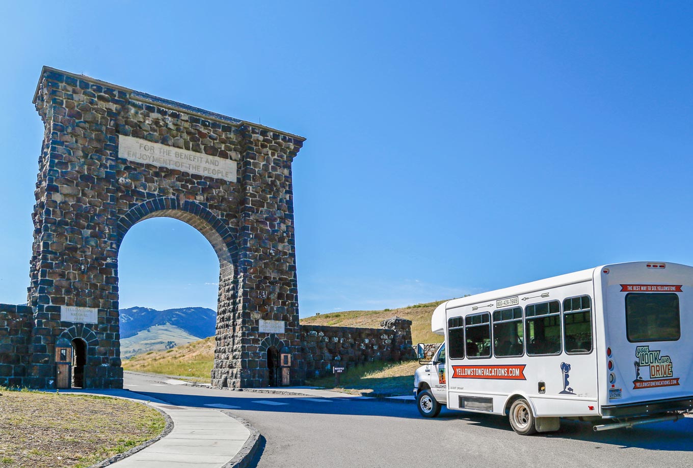 Yellowstone Vacation Tour bus from Gardiner, MT by the Roosevelt Arch at Yellowstone's north entrance